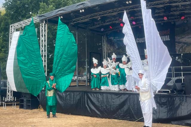 Children and adults in traditional costumes perform on stage.