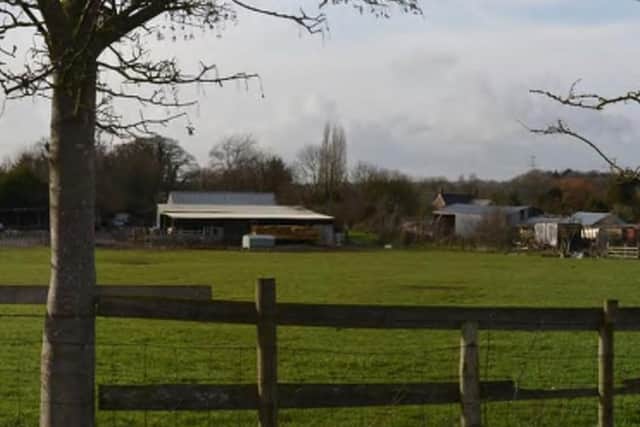 A view of the site with farm buildings in the background