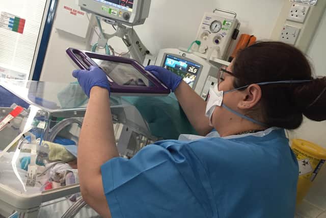 A member of L&D staff taking a video of a baby in NICU.