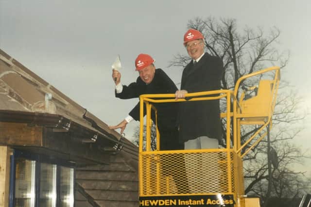 Local businessman Dennis Keech (left) laying the final roof tile