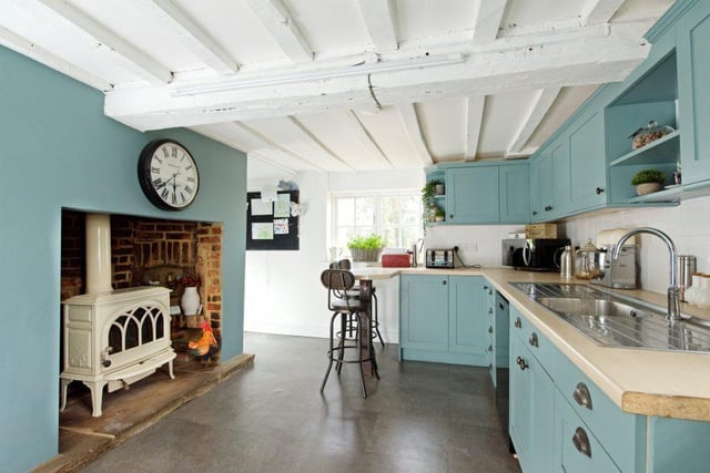 The spacious kitchen/breakfast room offers a range of base and wall units and inglenook with wood burner