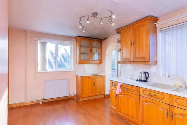 The kitchen has laminate work surfaces, a sink with a drainer, an integrated fridge, radiator, gas oven and hob with a cooker hood, and laminate flooring.