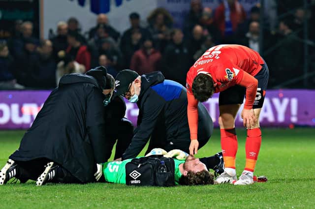 Jed Steer receives treatment on the Kenilworth Road pitch last night