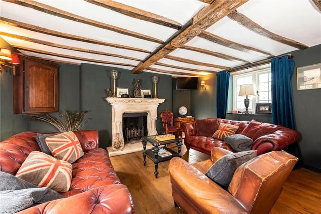 The family room has exposed ceiling beams, solid oak flooring and an open fireplace with a grate
