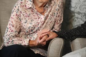Care home resident holds hands with her daughter. Picture: Andrew Matthews/PA