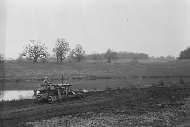 Nearly three months before the coronation pageant at the Luton Hoo, a worker can be seen preparing the grounds for the Merrie England performance