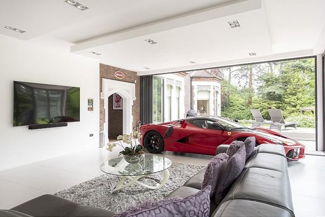 On the other side of the kitchen, sits a red Ferrari. The patio doors around the room open out onto the gardens