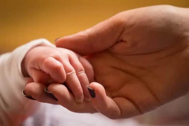 Mother holding the hand of a new baby. Picture: Dominic Lipinski via PA