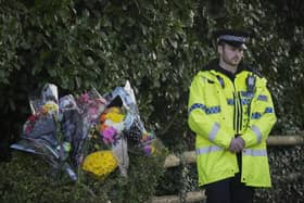 A police officer stands next to floral tributes at the entrance to Linear Park where 16-year-old Brianna Ghey was found with multiple stab wounds on a path in Culcheth (Photo by Christopher Furlong/Getty Images)