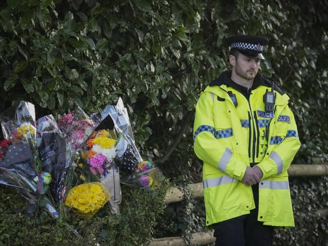 A police officer stands next to floral tributes at the entrance to Linear Park where 16-year-old Brianna Ghey was found with multiple stab wounds on a path in Culcheth (Photo by Christopher Furlong/Getty Images)