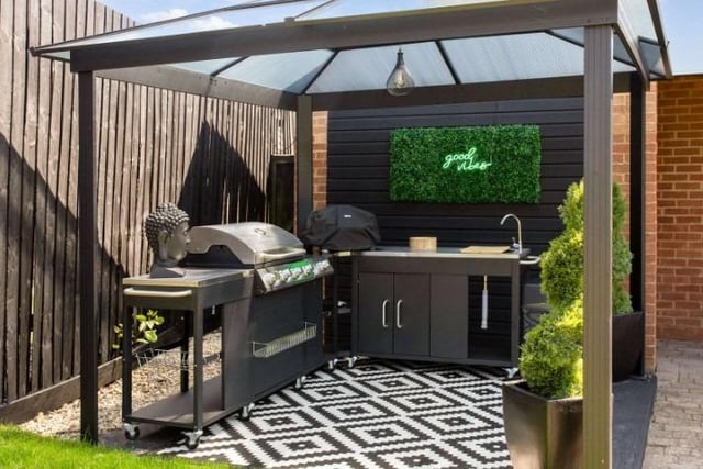 The home has a covered outdoor kitchenette with built-in barbeque area