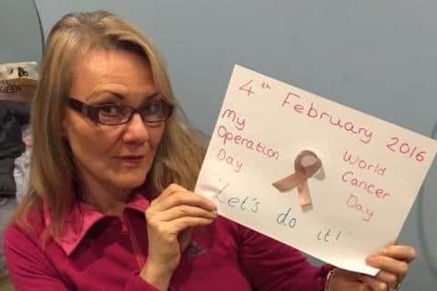 Cancer survivor Denise Coates holds up a handwritten poster the day before surgery on Cancer Awareness Day, 2016