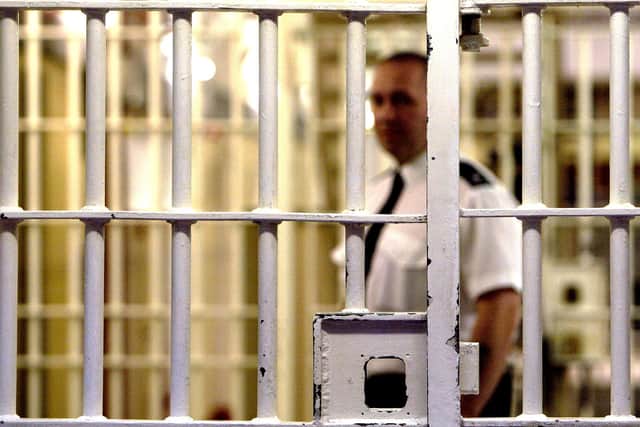 A prison guard at HMP Pentonville stands behind a locked gate. (Photo by Ian Waldie/Getty Images)