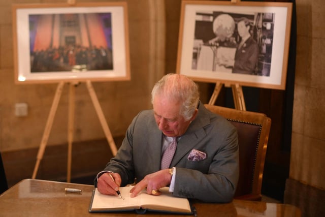 Britain's King Charles III signs the visitors' book as he visits Luton Town Hall  (Photo by DANIEL LEAL/POOL/AFP via Getty Images)