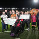 Tom Lockyer poses with Luton and Cherry trust fundraisers with cheques for the British Heart Foundation during the Premier League match. Photo by David Horn.