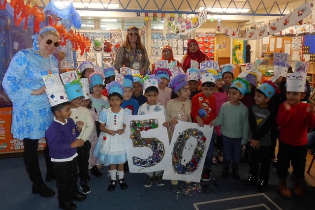 More students posed for a photograph with decorated hats and a giant '5' and '0' signs