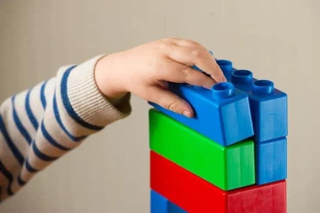 A preschool age child plays with plastic building blocks. Picture: Dominic Lipinski/PA