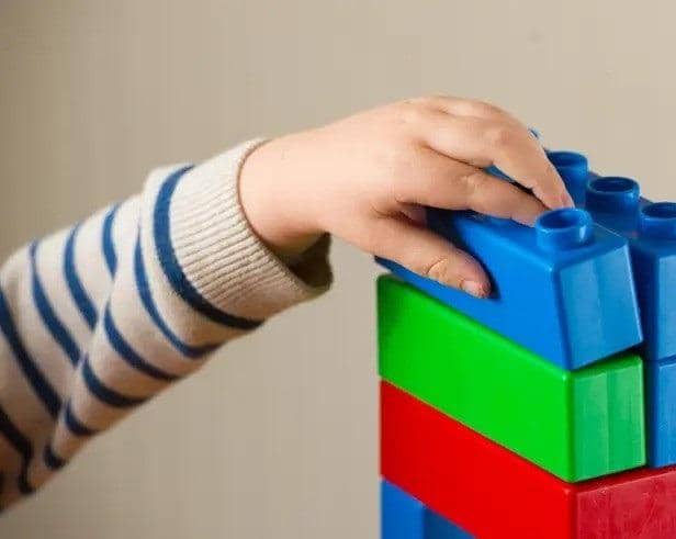 A preschool age child plays with plastic building blocks. Picture: Dominic Lipinski/PA
