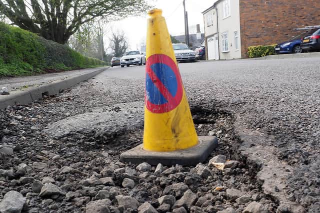 A traffic cone warns drivers of the pothole danger