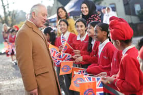 King Charles III smiles as he speaks with local school children waving flags during a visit to the newly built Guru Nanak Gurdwara (Photo by Chris Jackson/Getty Images)