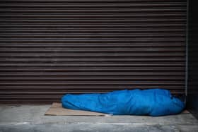 A homeless person sleeps in the entrance of a property. Photo by Carl Court/Getty Images