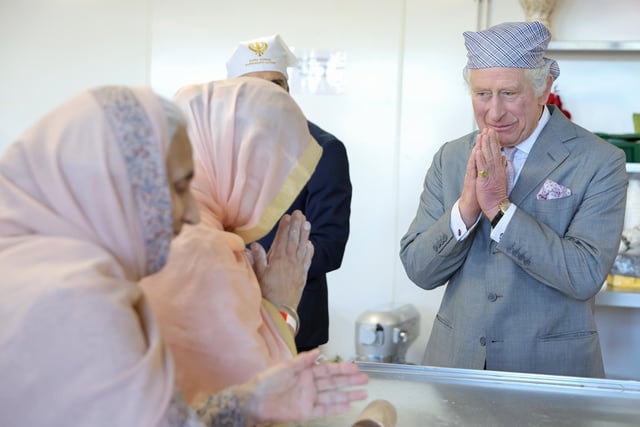 King Charles III makes the traditional namaste gesture as he speaks to volunteers (Photo by Chris Jackson/Getty Images)