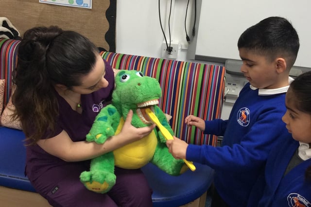 Children learning how to brush their teeth using a cuddly crocodile.