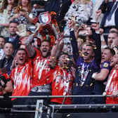 Sonny Bradley lifts the play-off winners' trophy at Wembley