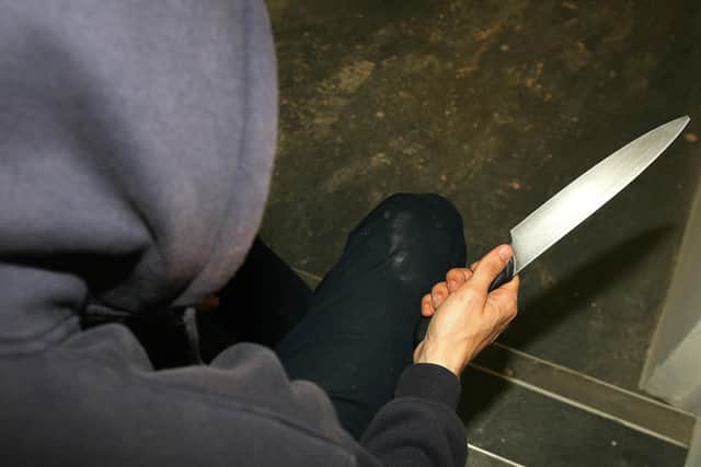 PICTURE POSED BY MODEL File photo of a man in a hoodie holding a knife. The number of young offenders cautioned or sentenced after being caught with knives has hit the highest level for nearly eight years.