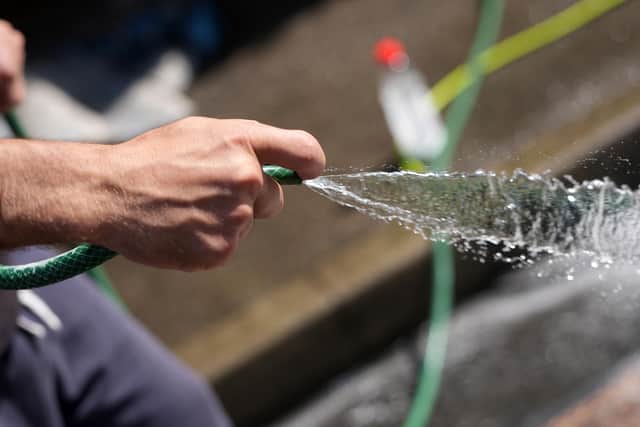 A man uses a hosepipe. Photo by Christopher Furlong/Getty Images)