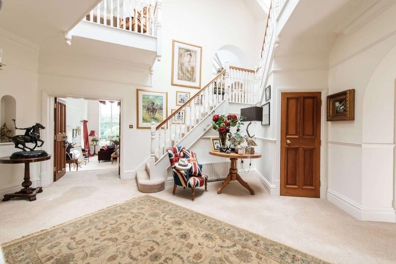 The porch opens onto an inner entrance hall, with a vaulted ceiling and staircase that opens the space up to the sky. The hall leads onto the great room - complete with cathedral-like proportions, a fireplace and balconies from the first-floor.