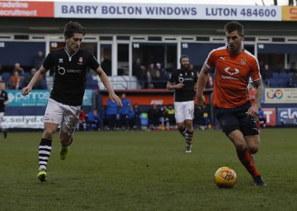 Alex Woodyward tracks James Collins during Lincoln's 4-2 defeat at Kenilworth Road