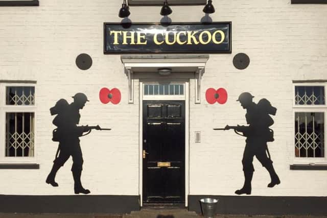 Soldier and Poppy cut outs on the Cuckoo pub wall facing the Village Green