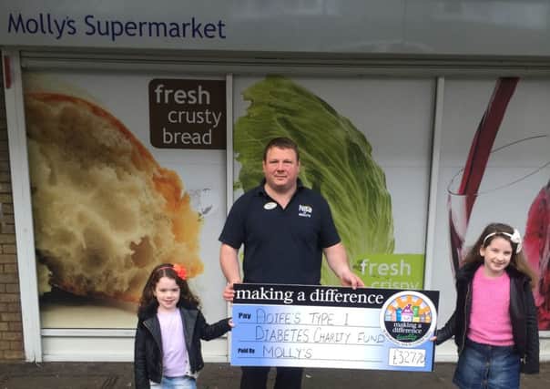 Aoife and her sister Bailey receive the cheque for Aoife's Type 1 Diabetes Charity Fund from Scott Jell, store manager