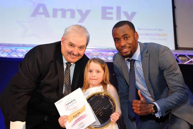 Six-year-old Amy Ely receives her Sports Personality of the Year award from Kola Adedoyin and LSN chairman Carl Richardson
