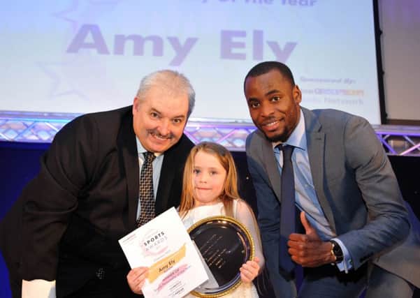 Six-year-old Amy Ely receives her Sports Personality of the Year award from Kola Adedoyin and LSN chairman Carl Richardson