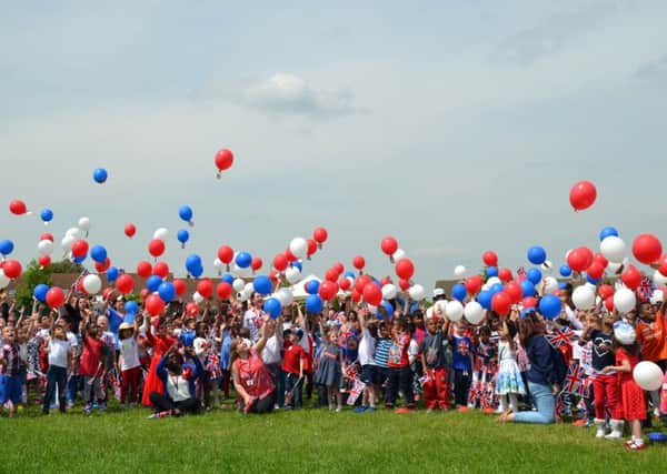 Pupils celebrate the Queen's 90th birthday by releasing hundreds of balloons